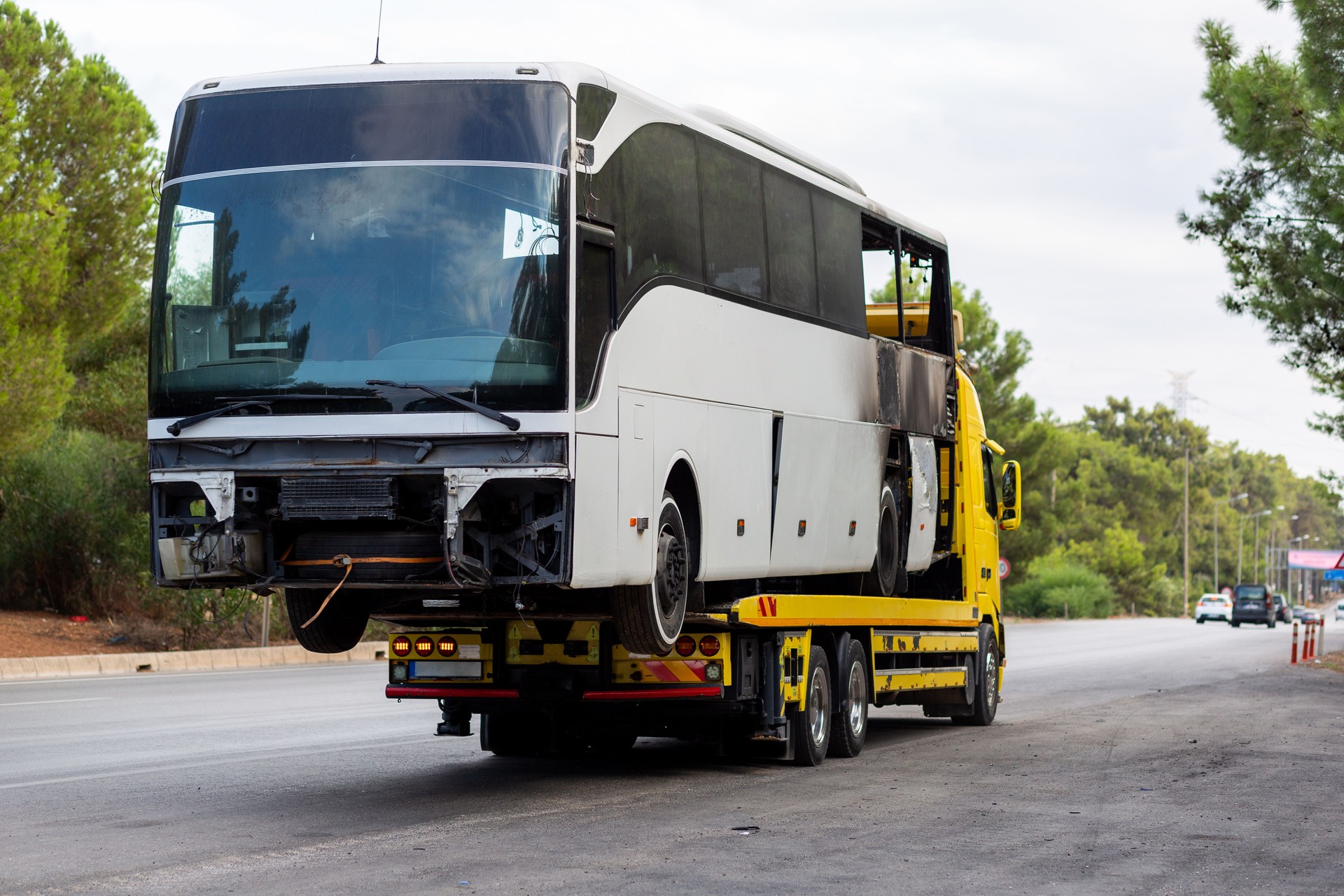 A tow truck carrying a burnt bus